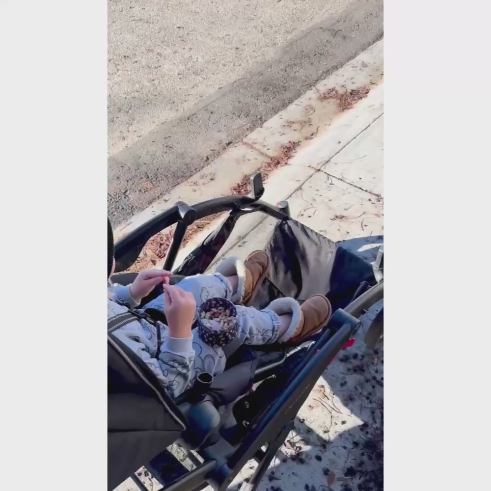 video showing wearabowl in use by a young child seated and buckled into their stroller snacking comfortably.